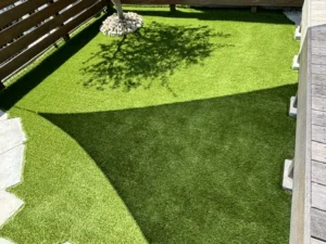 木を囲むように人工芝を敷いたお庭。木漏れ日が芝の上に落ちている